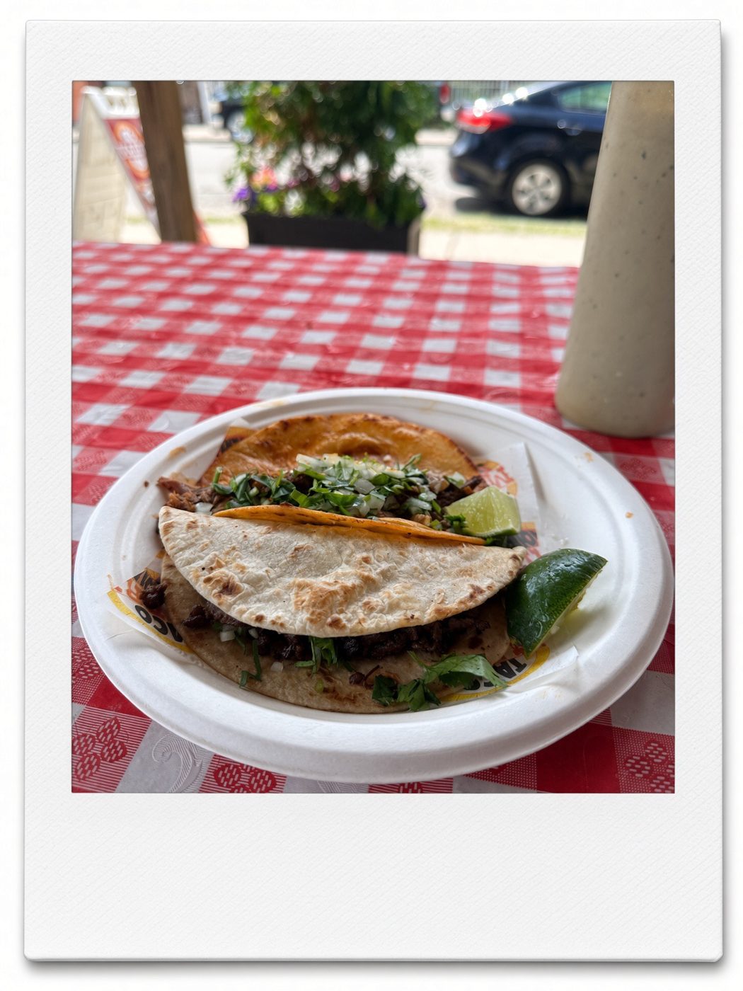 Birria and asada tacos with lime on a red gingham table at Taco Madre Taqueria, Detroit